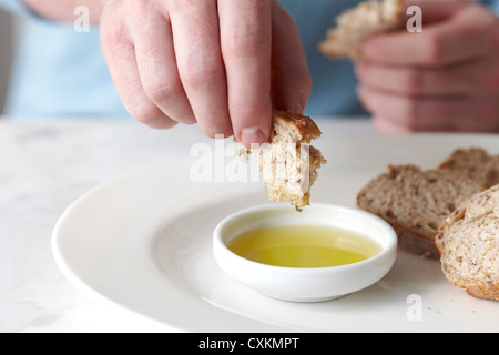 Man Dipping Baguette into Olive Oil Stock Photo