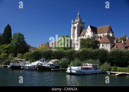 French church on riverside in Dole, with boats and barges on a bright Summer's day. Stock Photo