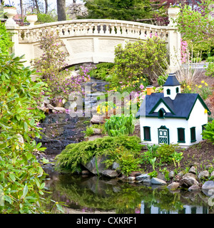 A public garden in Halifax, Nova Scotia featuring a small stream, garden bridge and a miniature model house. Stock Photo