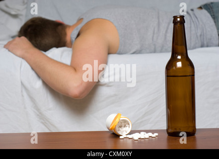 Beer bottle and pills on the table. Man sleeping on the sofa. Stock Photo