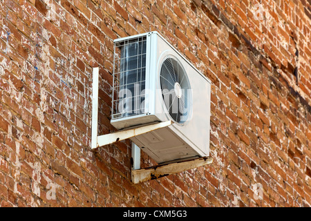 Air conditioning heat pump mounted on old brick wall. Stock Photo