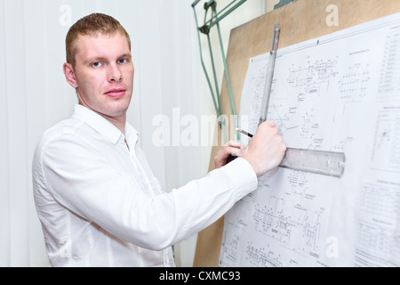 Engineer with blueprint standing near old drawing board Stock Photo