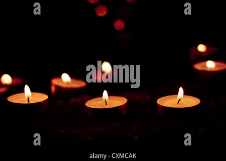 Tea light candles burning in the dark Stock Photo