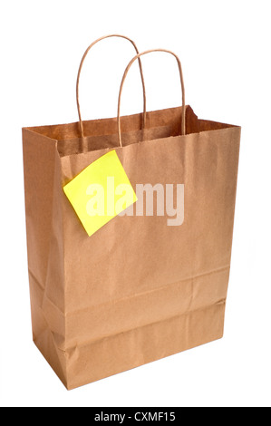 A brown shopping bag with handles with a post-it note or sticky note attached on a white background Stock Photo