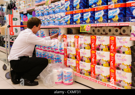 Store manager assists in stacking shelves in a Poundland shop store. Stock Photo