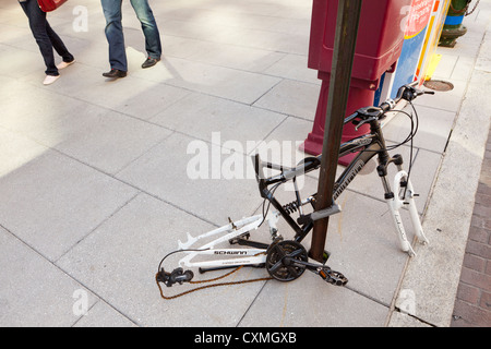 Vandalized bicycle on street sign post (vandalized bike frame) - USA Stock Photo