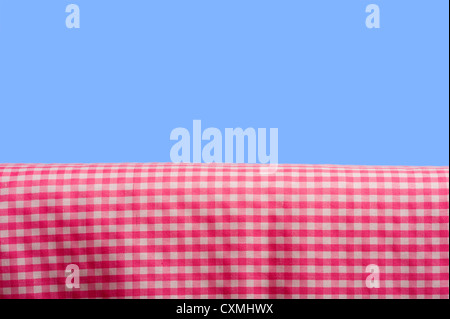 A background consisting of a pink gingham tablecloth on a blue sky background with copy space Stock Photo