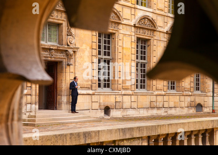 Coffee break in the courtyard of Hotel de Sully in Les Marais - viewed through ancient window frame, Paris France Stock Photo