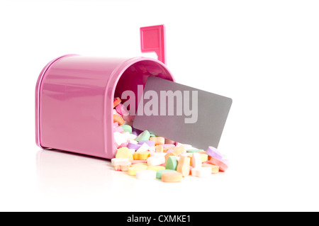 A pink mail box with conversation hearts and a blank notecard falling out on a white background, Valentine's Day, with copy space Stock Photo