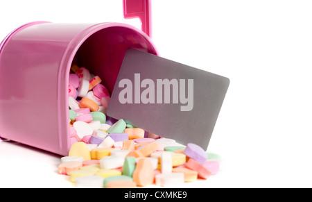 A pink mail box with conversation hearts and a blank notecard fallin out on a white background, Valentine's Day, with copy space Stock Photo