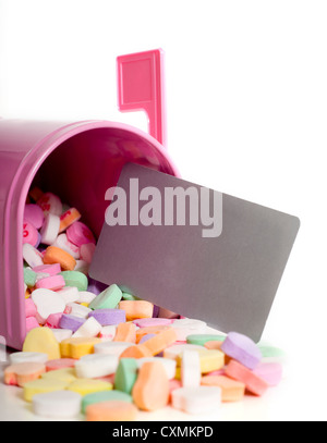 A pink mail box with conversation hearts and a blank notecard falling out on a white background, Valentine's Day, with copy space Stock Photo