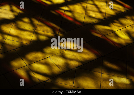 Yellow and red stained glass window light projected onto a church floor Stock Photo