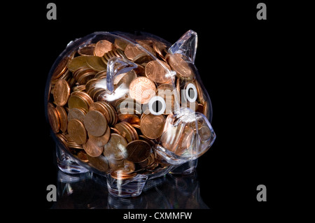 Clear piggy bank full of change on a black background Stock Photo