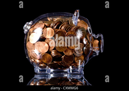 Clear piggy bank full of change on a black background Stock Photo