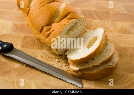 slicing bread on wood cutting board with a bread knife Stock Photo