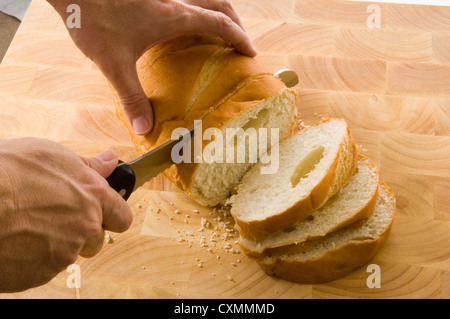 slicing bread on wood cutting board with a bread knife Stock Photo