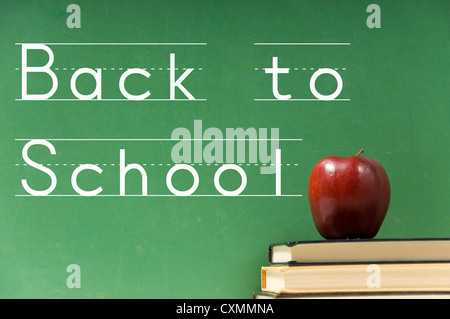School books and apple in front of school chalkboard with "Back to School" in script Stock Photo