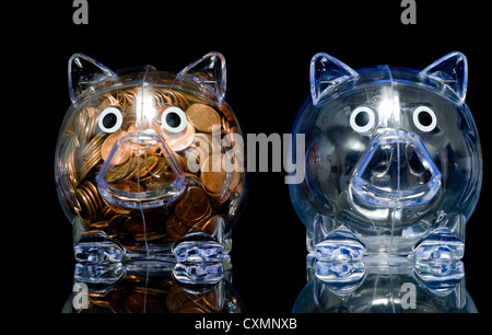 Two clear piggy banks one full of pennies and one empty Stock Photo