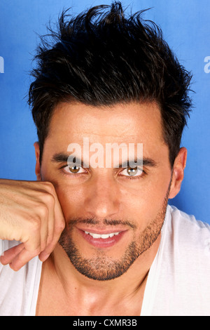 Smiling 30 years old man with black hair and brown eyes portrait over a light blue background Stock Photo