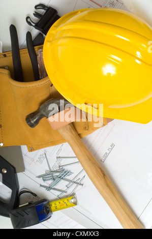 Blueprints with a yellow hard hat and tool belt with various tools Stock Photo