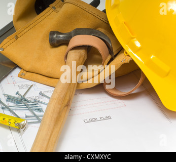 Blueprints with a yellow hard hat and tool belt with various tools Stock Photo