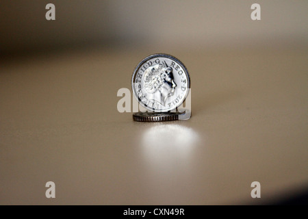 Five Pence Coins with slight reflection and shadows on blurred background, one coin on top of the other. Stock Photo