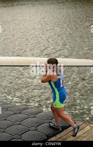 Woman helps move sculling craft on dock. Stock Photo