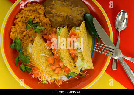 Mexican food plate with tacos, bean and rice on brightly colored plate Stock Photo