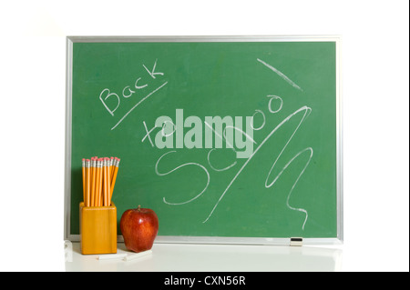 Green chalkboard with back to school message with an apple and a holder full of yellow pencils and pieces of chalk Stock Photo