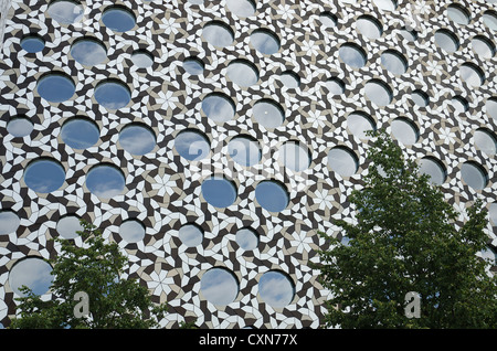 Modern architectural cladding with interlocking metallic shapes forms interesting pattern and backdrop with circular windows Stock Photo