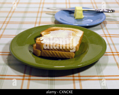 Buttered toast on a table top with butter and a knife in the background. Stock Photo