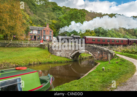Black Lion pub Consall on the Churnet Valley Railway with a steam train passing by over the Caldon canal in Staffordshire. Stock Photo