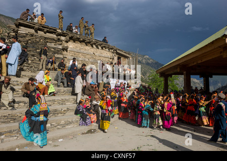 Kalash women and girls overlooked by security forces at the Grum Village Charso (dancing ground), Kalash Joshi (Spring Festival), Rumbur Valley, Chitral, Khyber-Pakhtunkhwa, Pakistan Stock Photo