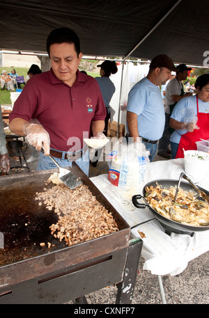 Hispanic male men tend to grill at outdoor food booth at church festival in Austin, Texas Stock Photo