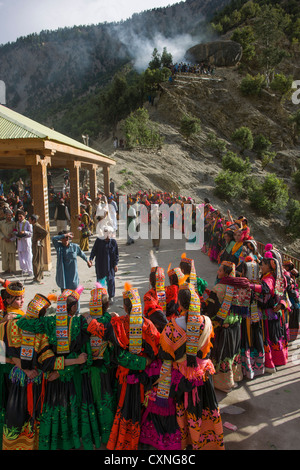 Kalash women and girls dancing at the Grum Village Charso (dancing ground), with the men's sacred area behind, Kalash Joshi (Spring Festival), Rumbur Valley, Chitral, Khyber-Pakhtunkhwa, Pakistan Stock Photo