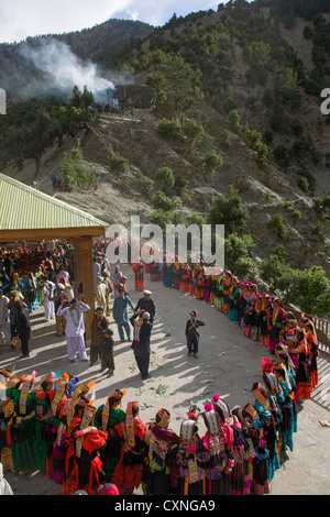 Kalash women and girls dancing at the Grum Village Charso (dancing ground), with the men's sacred area behind, Kalash Joshi (Spring Festival), Rumbur Valley, Chitral, Khyber-Pakhtunkhwa, Pakistan Stock Photo