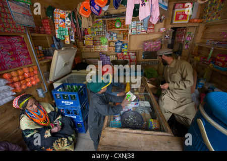 Muslim shopkeeper and his Kalash thaya (father's older brothers wife) in his shop at Krakl Village, Bumburet Valley, Chitral, Khyber-Pakhtunkhwa, Pakistan Stock Photo