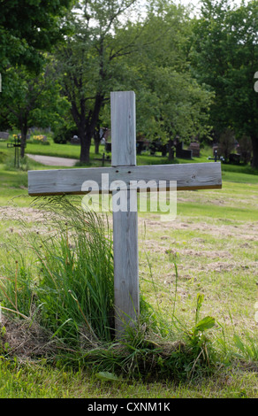 Simple, single wooden cross at a gravesite in an outdoor cemetery. Stock Photo