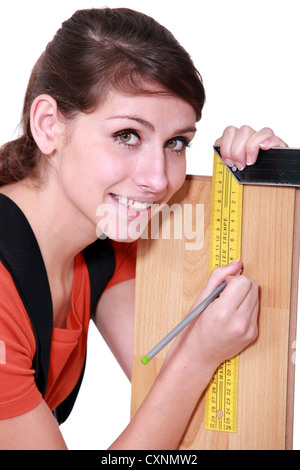 Female carpenter marking out wood with set-square Stock Photo