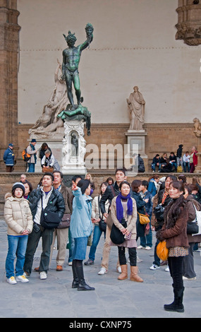 Piazza della Signoria statues, including Perseus Holding Head of Medusa, behind tourists in Florence Stock Photo