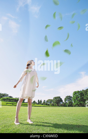 Young Woman Standing In Park With Arms Outstretched Stock Photo