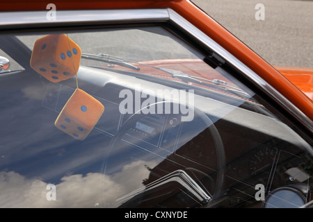 Pair large orange fuzzy furry dice hanging from rear view mirror, restored orange Ford Cortina Mark 3, Suffolk, UK Stock Photo