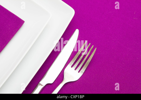 Mauve tablecloth with white square plates and mauve napkin Stock Photo