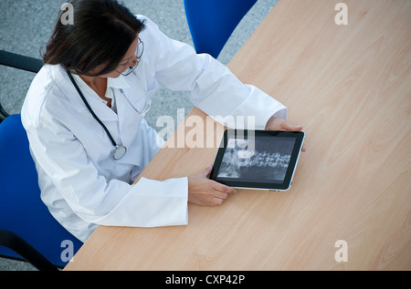 female doctor using ipad tablet computer seated at desk Stock Photo