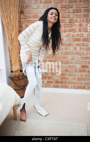 Woman getting dressed / putting her jeans on at home Stock Photo