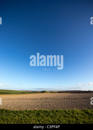View across a ploughed field towards Silbury Hill, an ancient neolithic monument consisting of an artificial chalk hill Stock Photo
