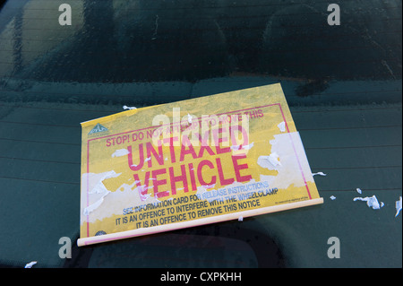 Sticker on the windscreen of an untaxed vehicle that has been wheelclamped on a street in England. Stock Photo