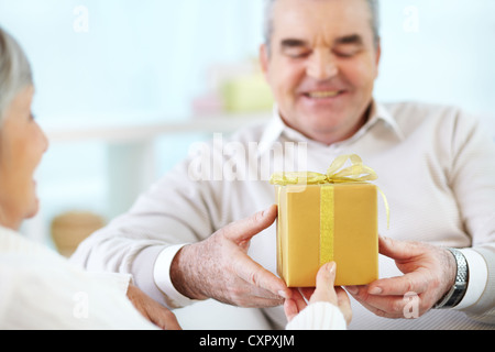 Close-up of mature man taking present from his wife Stock Photo