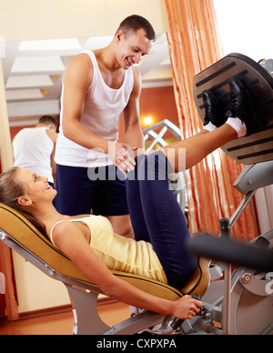 Portrait of sporty female doing physical exercise with young trainer helping her Stock Photo