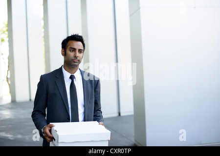 Businessman leaving office with box of personal items